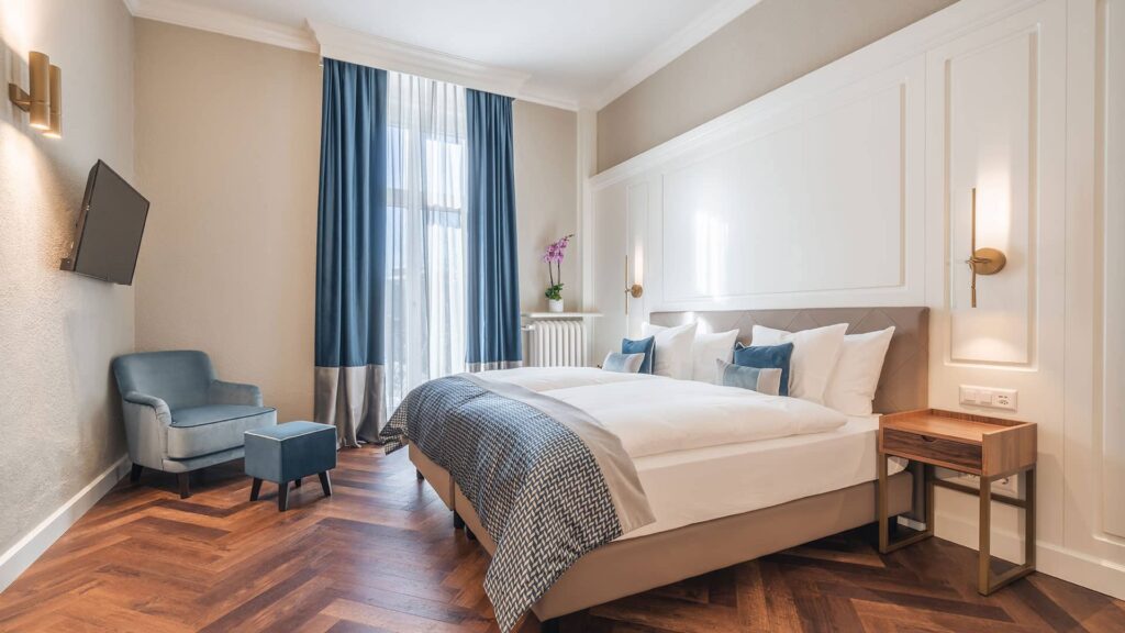 Erleben Sie die unaufdringlich royale Atmosphäre: Wohnraum mit Récamière, und begehbarem Kleiderschrank, elegantes Schlafzimmer und durchdachte Ambientebeleuchtung.