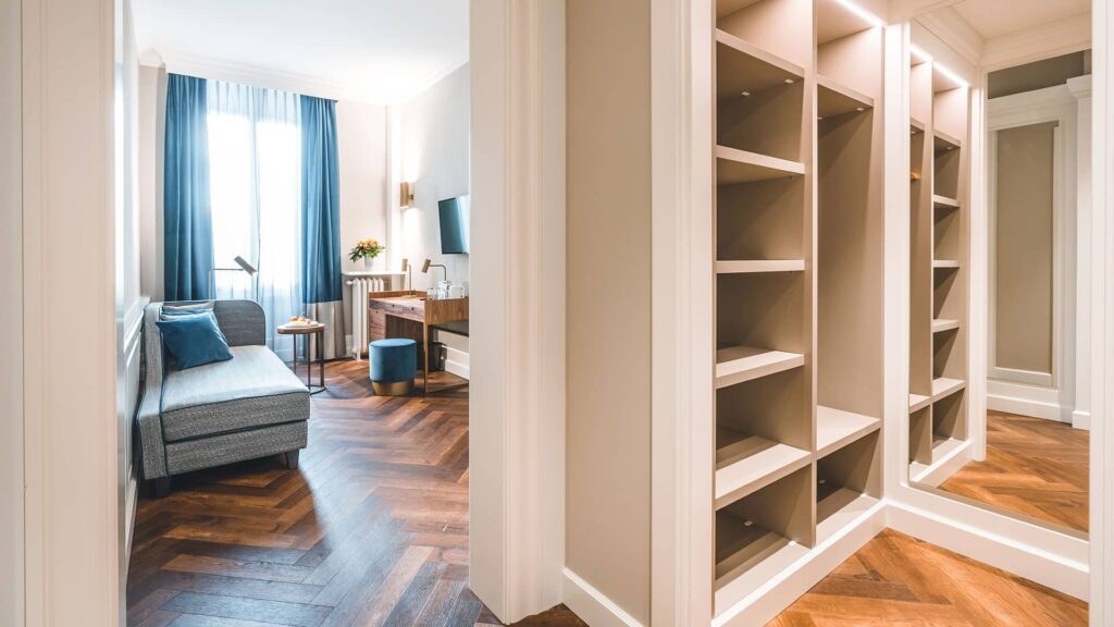 Erleben Sie die unaufdringlich royale Atmosphäre: Wohnraum mit Récamière, und begehbarem Kleiderschrank, elegantes Schlafzimmer und durchdachte Ambientebeleuchtung.